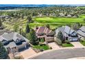 Aerial view of a tan and stone two-story home and golf course community at 7083 Turweston Ln, Castle Pines, CO 80108