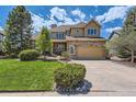 Tan and stone two-story home featuring a well-kept lawn and a spacious two-car garage at 7083 Turweston Ln, Castle Pines, CO 80108