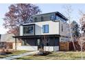 Striking modern home featuring a flat roof, landscaped yard, inviting covered porch, and large windows at 2471 Quitman St, Denver, CO 80212