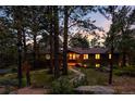 Inviting single-story home with stone accents and warm interior lighting at dusk at 2907 Hiwan Dr, Evergreen, CO 80439