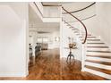 Bright foyer with a winding staircase, white trim, hardwood floors, and an open view of the kitchen beyond at 2540 S Monroe St, Denver, CO 80210