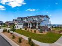 The beautiful home features a three-car garage, a combination of stone and siding, and a well-manicured front yard at 9566 Poppy Way, Arvada, CO 80007