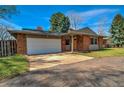 Brick home featuring a two-car garage and manicured landscaping at 1705 Stonehenge Dr, Lafayette, CO 80026