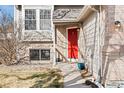 Welcoming front entrance with a bright red door, brick accents, and neatly landscaped yard at 9905 Foxhill Cir, Highlands Ranch, CO 80129