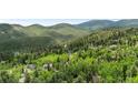 Beautiful aerial view of a home nestled among lush trees and rolling hills at 32171 Lodgepole Dr, Evergreen, CO 80439