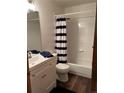 Clean bathroom with a single sink vanity, blue towels, and a shower/tub combo with striped curtain at 9724 W Euclid Dr, Littleton, CO 80123
