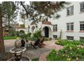 Charming white stucco home featuring arched doorways, a tile roof, a stone patio with a fountain, and colorful landscaping at 844 N Humboldt St # 5, Denver, CO 80218