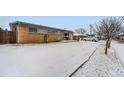 Brick house with a snow-covered yard and mature trees on a sunny day at 3108 Quari St, Aurora, CO 80011