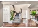 Bright foyer featuring hardwood floors, staircase with modern railings, and a view into the dining area at 6227 Shenandoah Ave, Firestone, CO 80504