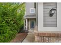 Inviting front entrance with a well-lit porch, tidy landscaping, and charming brick accents at 6227 Shenandoah Ave, Firestone, CO 80504