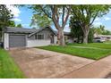 Quaint single-story home featuring a garage, driveway, and well-maintained lawn with mature trees at 806 S Jersey St, Denver, CO 80224