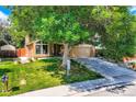 Charming single-Gathering home featuring a lush green lawn, mature trees, and a two-car garage at 8845 W 81St Dr, Arvada, CO 80005