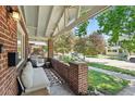 Inviting front porch with brick detail, hanging chair, and comfortable seating area at 3437 W 35Th Ave, Denver, CO 80211