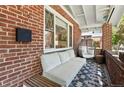 Inviting front porch with brick detail, hanging chair, and comfortable seating area at 3437 W 35Th Ave, Denver, CO 80211