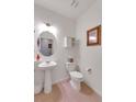 A stylish half-bathroom featuring a pedestal sink, modern toilet, decorative mirror, and tiled floors at 1800 Vantage Pkwy, Berthoud, CO 80513