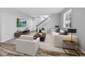 Bright living room with wood-look flooring, white sofas, contemporary furnishings and a staircase at 25584 E Byers Dr, Aurora, CO 80018