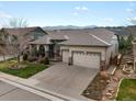 Suburban home with a three-car garage, manicured lawn, garden feature, and mountain views at 8501 Hackamore Rd, Littleton, CO 80125