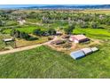 Gorgeous aerial view of a multi-acre property featuring lush green fields, a house, and multiple outbuildings at 11475 Us Highway 85, Littleton, CO 80125