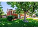 Traditional brick home with a lush front lawn and a large shade tree, offering curb appeal and a welcoming ambiance at 5945 W Colgate Pl, Denver, CO 80227