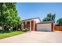 Red brick home with a spacious driveway leading to a two-car garage, complemented by green landscaping at 5945 W Colgate Pl, Denver, CO 80227