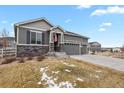 Charming two-story gray home with stone accents, three-car garage, and an American flag at 5723 Berry Ridge Way, Castle Rock, CO 80104
