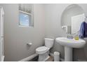 Modern powder room with a pedestal sink, round mirror, and natural light at 918 Honey Berry Ct, Elizabeth, CO 80107