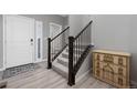 Inviting entryway features stairs with modern dark wooden railings and light hardwood flooring at 918 Honey Berry Ct, Elizabeth, CO 80107