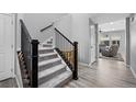 Light grey carpeted staircase with dark wood railing and light hardwood floors at 918 Honey Berry Ct, Elizabeth, CO 80107