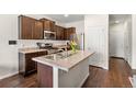 Beautiful kitchen with stainless appliances, kitchen island, dark wood cabinets, and hard wood floors at 1518 Sepia Ave, Longmont, CO 80501