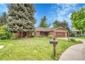 Charming brick home with lush front lawn, mature trees, tidy landscaping, and a two-car garage at 5964 S Florence Ct, Englewood, CO 80111