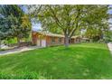 Well-maintained brick home with mature trees, a green lawn, and an attached two-car garage in a peaceful neighborhood at 2311 Emery Pl, Longmont, CO 80501