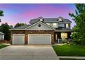 Beautiful two-story home with a stone accent garage, manicured lawn during twilight at 14675 Golden Eagle Run, Broomfield, CO 80023