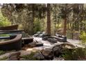 Beautiful backyard setting, featuring a pool, water feature and outdoor seating area amidst mature trees at 1070 Cypress Way, Castle Rock, CO 80108