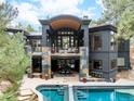 Stunning home exterior with a pool, balcony, stone accents, and manicured landscaping, offering luxurious outdoor living at 1070 Cypress Way, Castle Rock, CO 80108