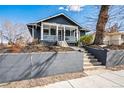 Inviting blue two-story home boasting a well-maintained yard, mature trees, and concrete stairs to the front porch at 5094 Meade St, Denver, CO 80221