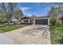Charming ranch home featuring a two-car garage and a well-maintained front yard with mature trees and a long driveway at 130 S Eaton St, Lakewood, CO 80226