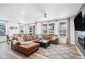 Open-concept living room featuring a brown leather sectional, modern lighting, and large windows at 2598 Knobbie Cir, Castle Rock, CO 80109