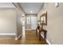 Neutral hallway with hardwood flooring, white trim, decorative accents, and a view to the front door at 10660 Winding Pine Pt, Highlands Ranch, CO 80126