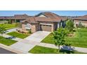 Low aerial view of stone accented home with a manicured lawn, brown roof, and two car garage at 25019 E Alder Dr, Aurora, CO 80016