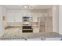 Well-equipped kitchen featuring granite countertops, stainless steel appliances, and sleek white cabinets at 5550 W 80Th Pl # 1, Arvada, CO 80003