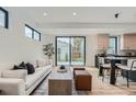 Bright living room with white walls, modern decor, and a view of the backyard through large sliding glass doors at 1928 W 41St Ave, Denver, CO 80211