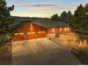 Expansive home exterior featuring a three-car garage, well-lit landscaping, and inviting curb appeal at dusk at 10963 N Chatfield Dr, Littleton, CO 80125