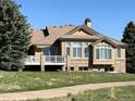 Rear view of house featuring a deck, large windows, stone accents, and a beautifully maintained lawn at 6772 Vista Lodge Loop, Castle Pines, CO 80108