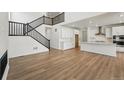 Bright living room with wood flooring, white walls, staircase, and open floor plan to the kitchen with a center island at 7291 Prairie Sage Pl, Littleton, CO 80125