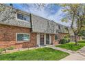 View of a brick townhome row with green lawns and mature trees showcasing the community's curb appeal at 15139 E Wesley Ave, Aurora, CO 80014