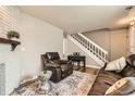 Inviting living area with a stone fireplace, leather furnishings, hardwood floors and a staircase at 15139 E Wesley Ave, Aurora, CO 80014