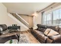 Cozy living room featuring a leather sofa, adjacent to a staircase, with a neutral color palette at 15139 E Wesley Ave, Aurora, CO 80014