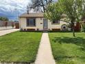 Lovely single-story house showcasing a green lawn, walkway, and decorative touches like flower boxes and a wagon wheel at 4825 Estes St, Arvada, CO 80002