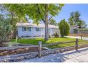Charming single-story home with manicured lawn, wood fence, mature trees, and inviting curb appeal at 7930 Poplar St, Commerce City, CO 80022