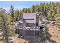 Multi-level mountain home with a large deck perfect for entertaining and a fully fenced yard surrounded by tall pine trees at 6574 Olympus Dr, Evergreen, CO 80439
